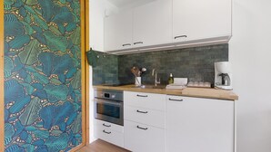 Una cucina moderna con mobili bianchi, un piano di lavoro in legno, forno integrato e una schiena di caminetto con motivo a foglia.