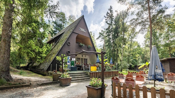 Un chalet rustique doté d’un toit en pente, d’une terrasse en bois et d’un espace salon extérieur.
