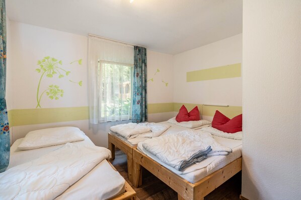 A room with two beds, a window with curtains, and wall decorations.