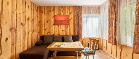 A wooden-paneled room with a sofa, a table, and a chair.