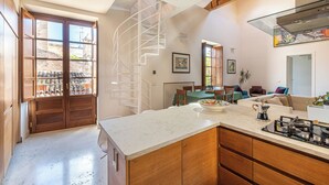 A modern kitchen with a marble countertop, wooden cabinets, and a spiral staircase. - San Salvatore Apartment by Wonderful Italy (Palermo)