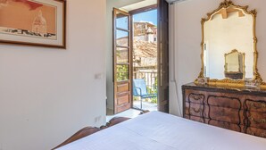 A bedroom with a bed, a dresser with a mirror, a framed picture on the wall, and an open door leading to a balcony. - San Salvatore Apartment by Wonderful Italy (Palermo)