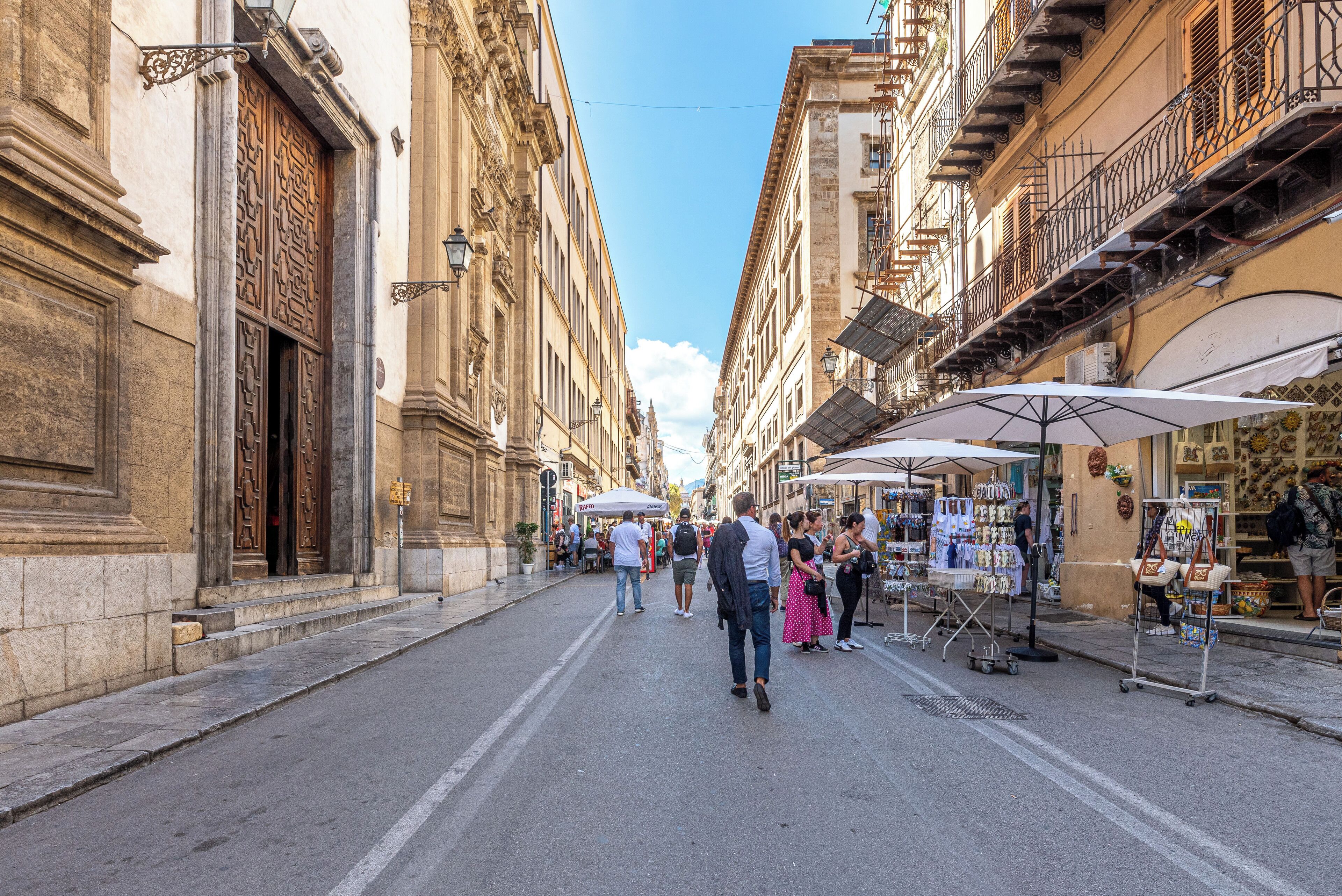 A street with buildings, shops, and people.