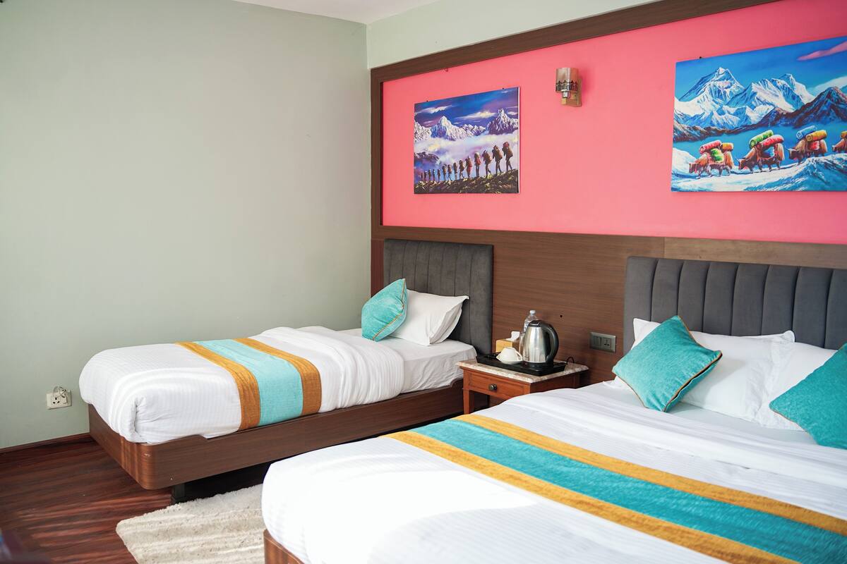 A hotel room with two beds, a nightstand, and artwork on the walls.