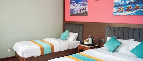 A hotel room with two beds, a nightstand, and artwork on the walls.