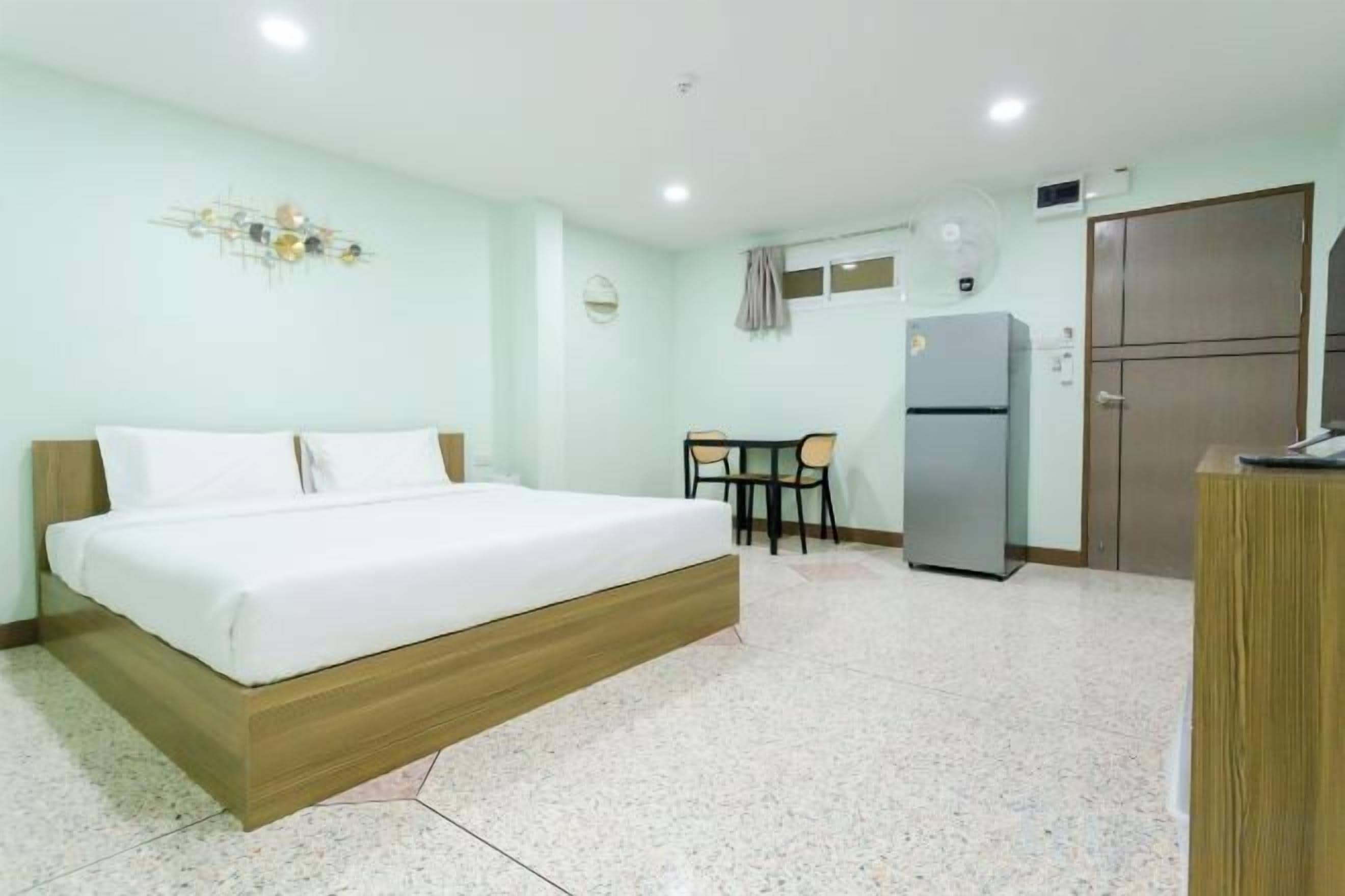 A hotel room with a bed, a desk, a refrigerator, and a wardrobe.