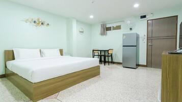 A hotel room with a bed, a desk, a refrigerator, and a wardrobe.