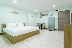 Una habitación de hotel con una cama, un escritorio, un refrigerador y un armario.