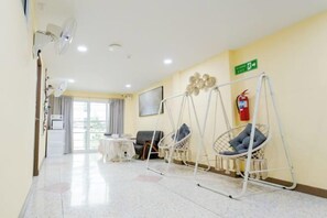 A hotel room with a swing chair, a fire extinguisher, a ceiling fan, and a view of the outside. - Rama Residency Sukhumvit Bangkok (Bangkok)