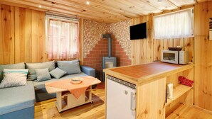 Un interior de madera con un sofá, una mesa pequeña, un microondas y un refrigerador compacto.