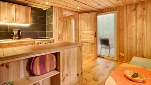 Un interior de madera con una cocina, un gran ventanal corredero y una zona de estar.