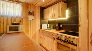 Una cocina compacta con armarios de madera, un microondas, una estufa y un lavamanos.