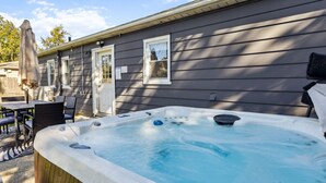 Ett bubbelbadkar framför ett hus med en uteplats, ett bord och stolar.