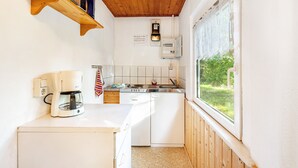 Una cucina compatta con macchina del caffè, lavastoviglie e una finestra vista sul verde.