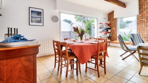 A dining area with a brick wall, a large window, and a view of the outdoors. - 700m from the beach, garden, 4 adults 2 children (La Guérinière)