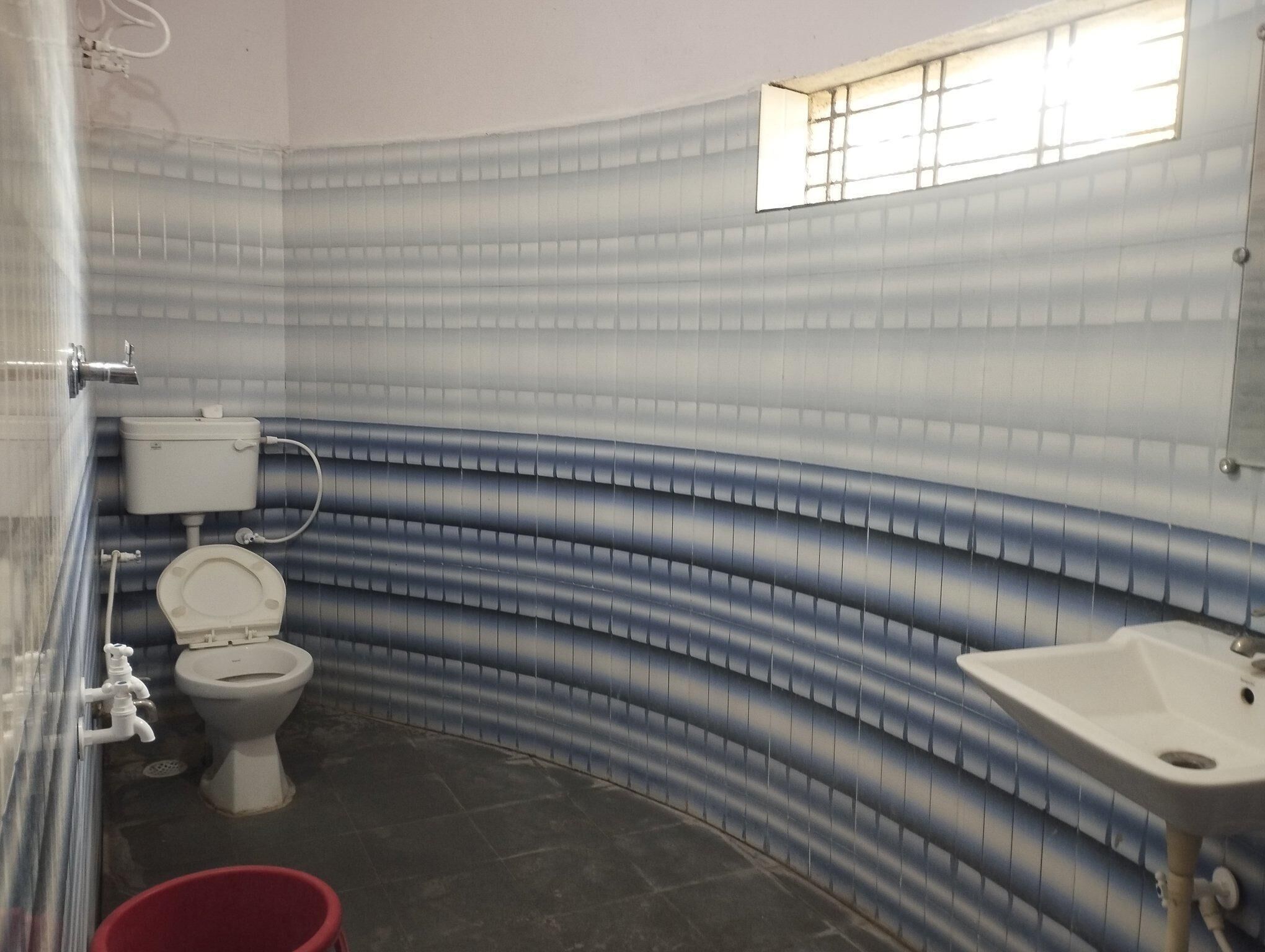 A bathroom with a toilet, a sink, and a window.