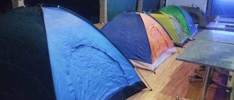 A row of tents with a table and chairs in a covered area.