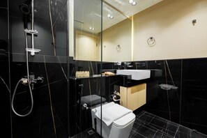 A modern bathroom with a glass-enclosed shower, a white sink, and a toilet.