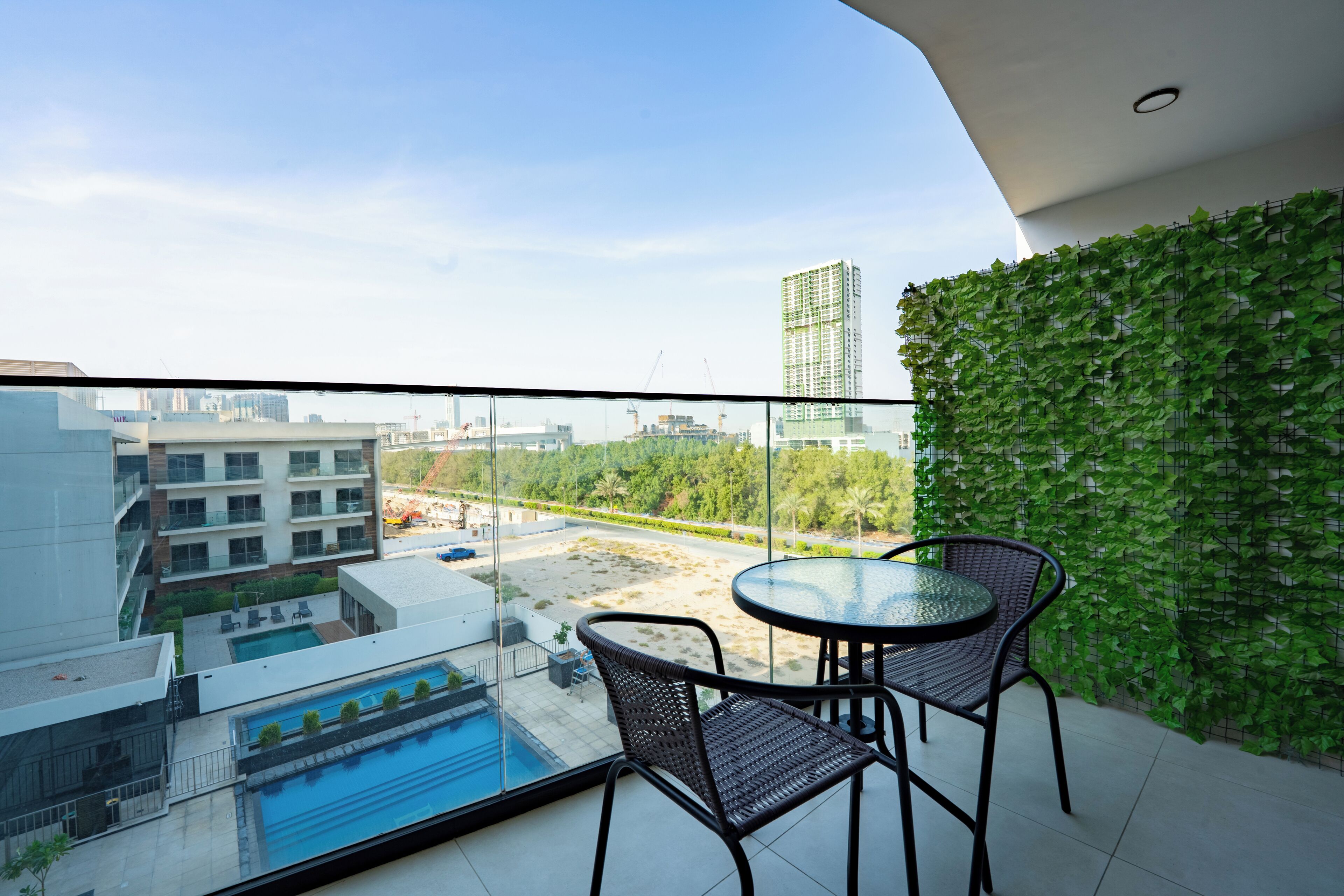A balcony with a glass railing, a pool, and a view of a cityscape.