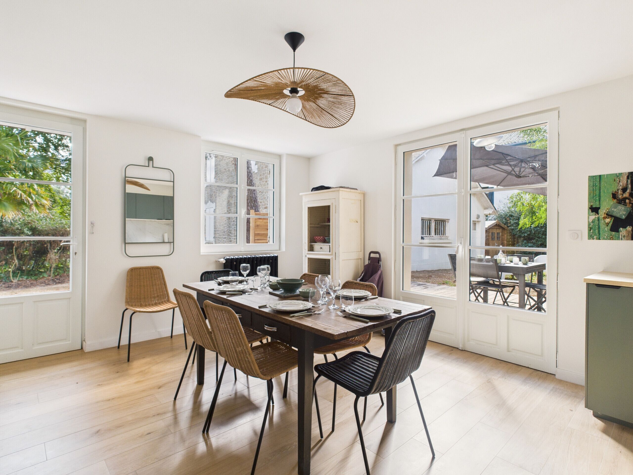 A dining area with a wooden table, four chairs, and a hanging light fixture.