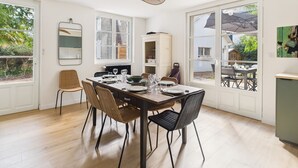 A dining area with a wooden table, four chairs, and a hanging light fixture. - 250m from beach - house for 6 adults/2 kids (Pornichet)