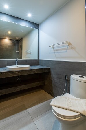 A modern bathroom with a large mirror, a sink, a toilet, and a towel rack. - Pool View 1 Bed Apt T2-720 (Chalong)