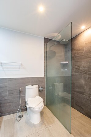 A modern bathroom with a glass-enclosed shower, a toilet, and a towel rack. - Pool View 1 Bed Apt T2-720 (Chalong)