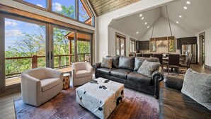 A spacious living area with a high ceiling, large windows, and a view of the outdoors. - Golden Sunsets at Eagles Nest - hot tub, view, community amenities (Banner Elk)