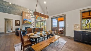 A spacious dining area with a long wooden table, leather chairs, and a hanging light fixture. - Golden Sunsets at Eagles Nest - hot tub, view, community amenities (Banner Elk)