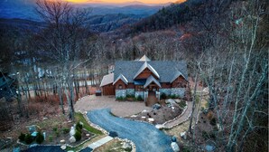 A lodge with a stone facade, multiple gabled roofs, and a gravel driveway. - Golden Sunsets at Eagles Nest - hot tub, view, community amenities (Banner Elk)