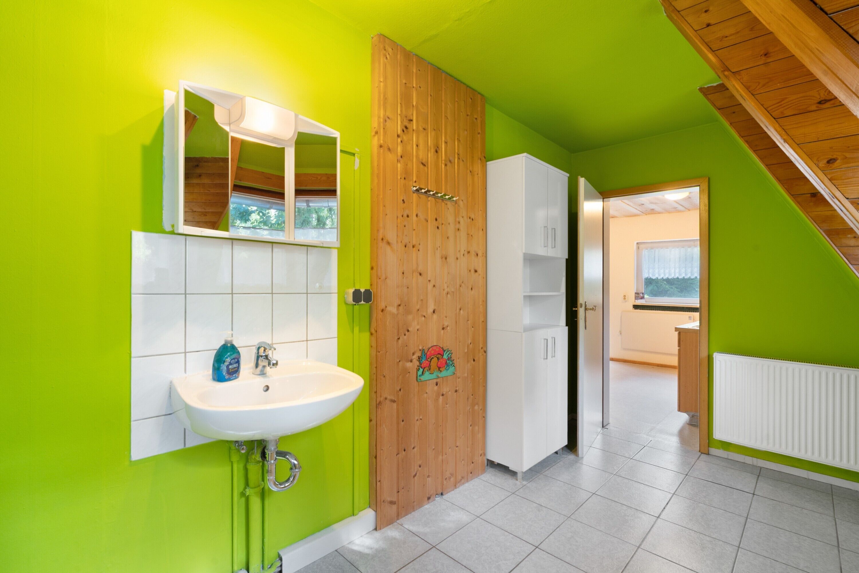 Ein Badezimmer mit Waschbecken, Spiegel und Holztür.