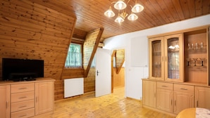 Ein Zimmer mit Holzwänden, einem Fernseher, Schränken und einer Treppe.