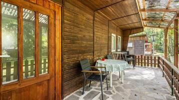 Une cabane en bois avec un plancher en pierre, un patio couvert avec des tables et des chaises, et une clôture en bois.