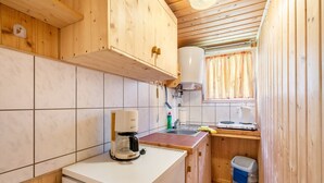 Una cucina compatta con mobili in legno, una macchina da caffè, un lavello e una finestra con tende.