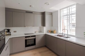 Une cuisine moderne dotée d’appareils électroménagers intégrés, d’une grande fenêtre et offrant une vue sur la ville.