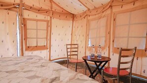 A tented room with a bed, two chairs, a small table with a bottle, and a window. - Bhati Desert Camp Raisar Bikaner (Bikaner)