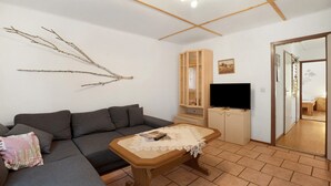 Ein Wohnzimmer mit einer Couch, einem Holztisch, einem Fernseher und einem Schrank.