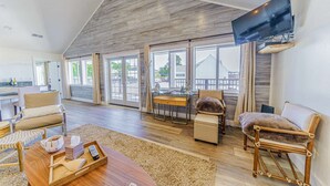 A spacious living room with a high ceiling, large windows, and a flat-screen TV mounted on the wall. - 3 Coastal View Houses in 1: Seaview 3BD+ Seasong 2BD* + Selah 4BD (Crescent City)