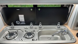 A compact kitchen with a sink, two gas stoves, and a faucet. - Glen Roamer VW Campervan – Explore Scotland in Comfort & Freedom (Dunblane)