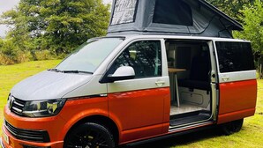 A red and white van with a roof tent, parked on grass with trees in the background. - Glen Roamer VW Campervan – Explore Scotland in Comfort & Freedom (Dunblane)