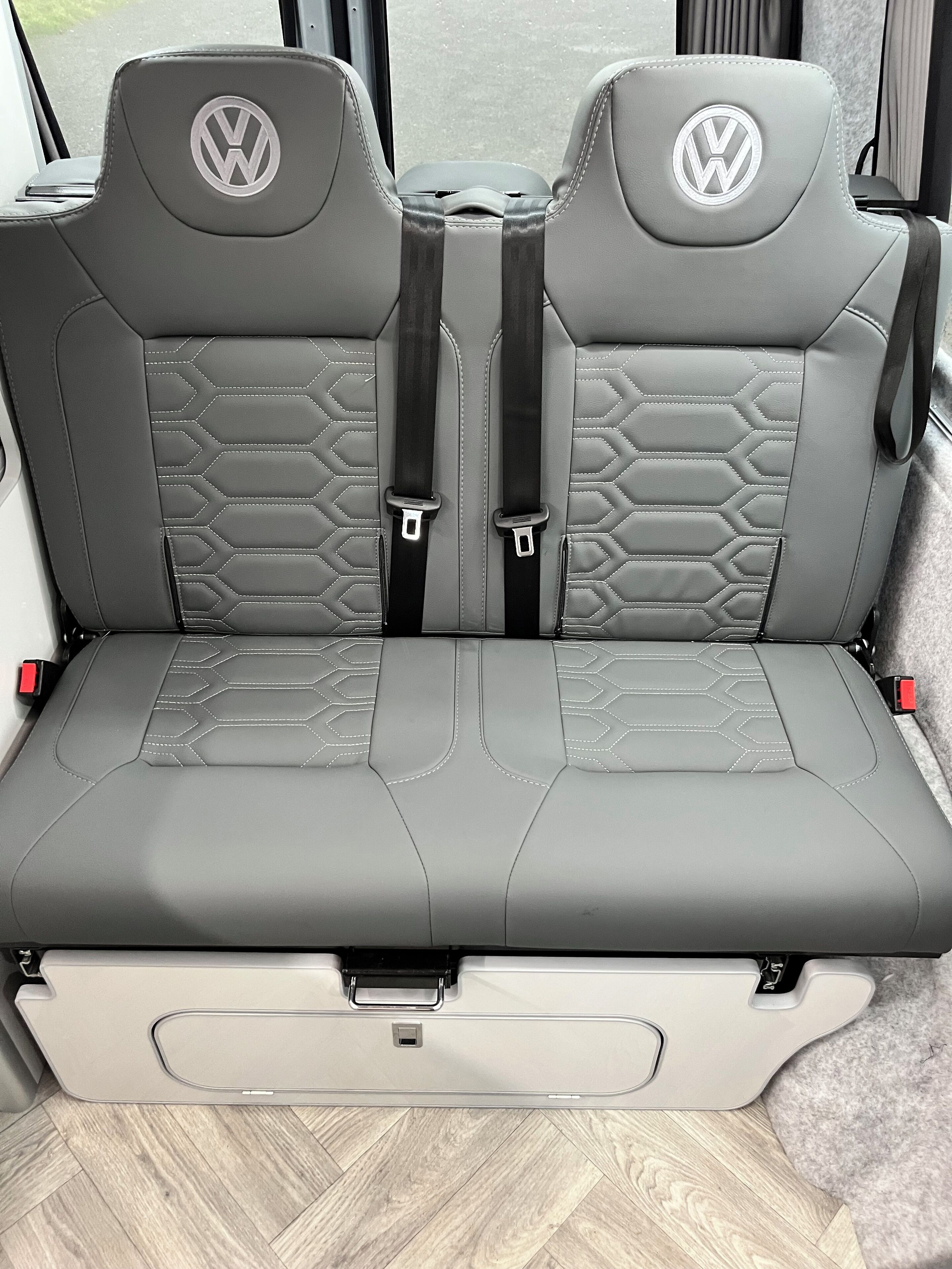 A vehicle interior with two seats featuring a geometric pattern and a central console.