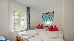 Une chambre d’hôtel avec deux lits, une fenêtre avec des rideaux et une œuvre d’art accrochée au mur.