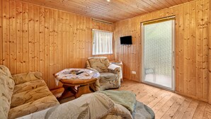 Una habitación con paneles de madera, un sofá, un sillón y una pequeña mesa con papeles.