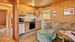 Un interior de madera con una kitchenette, un sofá y una mesa de comedor.