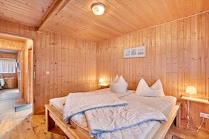 A wooden-paneled room with a bed, bedside lamps, and a framed picture on the wall.