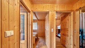 Un interior de madera con un pasillo que conduce a un dormitorio con cama y ventana.