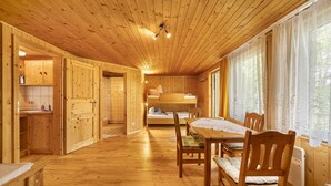 A wooden interior with a bunk bed, a dining table with chairs, and a kitchen area. - Bungalow '1 - Kimbucht' with Private Terrace and Shared Garden (Waldhufen)