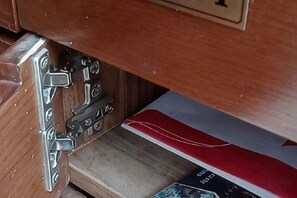 Un meuble en bois doté d’un loquet métallique et d’un objet rouge et blanc, dont on ne voit qu’une partie.