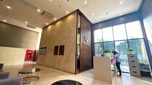 Een moderne lobby met een receptiebalie, zithoek en grote ramen.