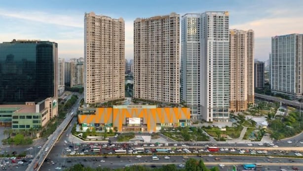 Een hoog gebouwde complex met meerdere woontorens, een centraal gelegen plein met een opvallende oranje constructie, en omliggende wegen met matig verkeer.